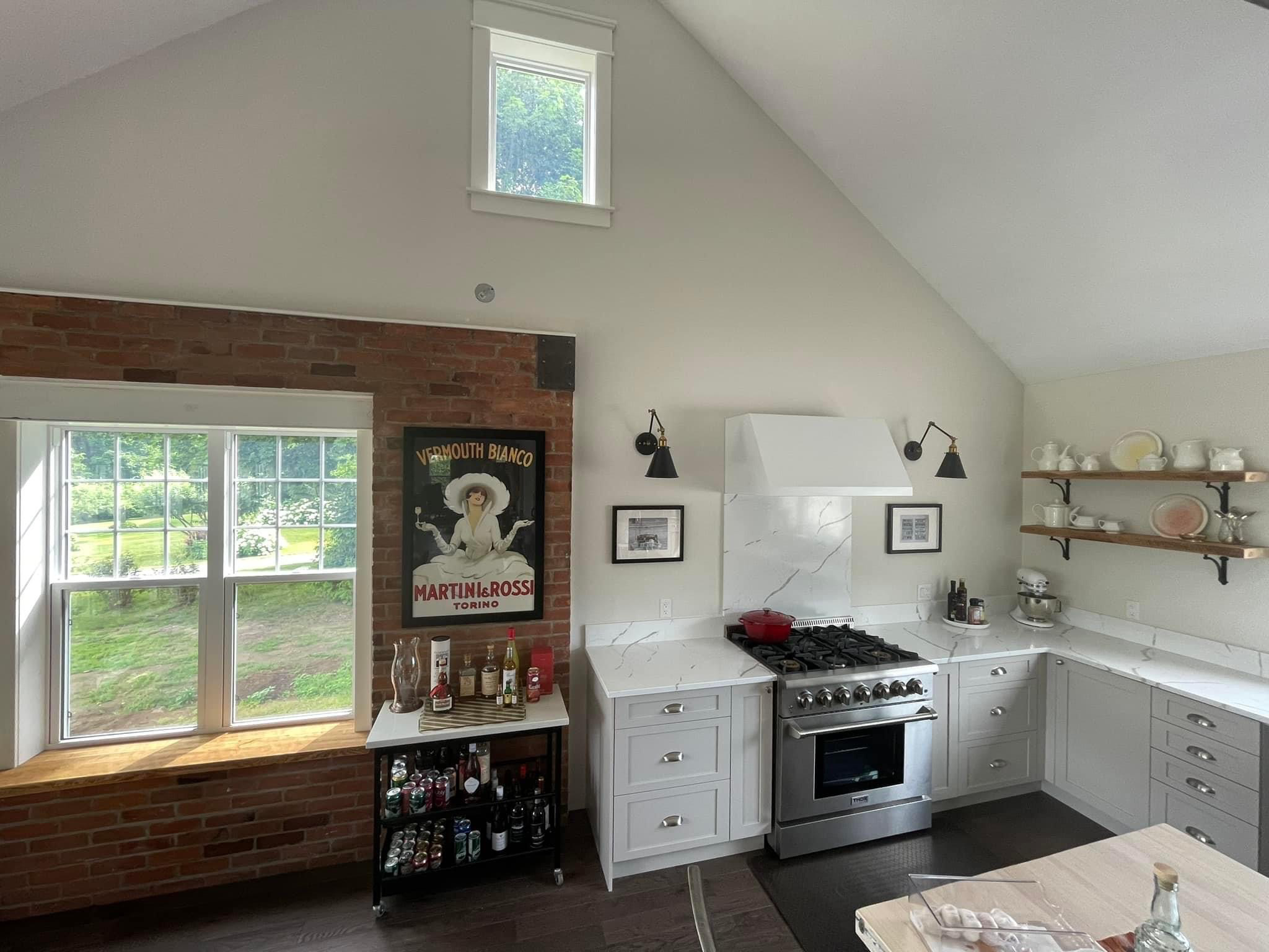Wide view of open-concept country kitchen with exposed red brick and custom cabinets